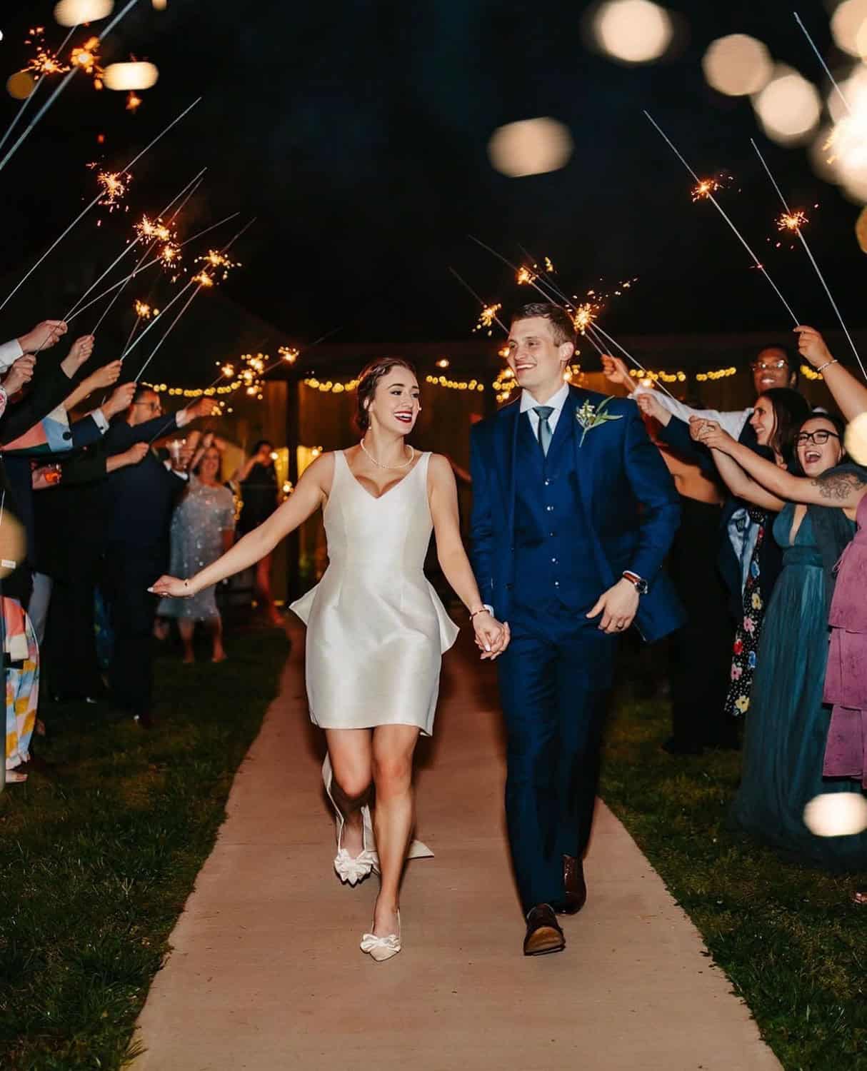 Couple walking hand-in-hand at wedding reception with sparklers at Mountain Ridge Venue.