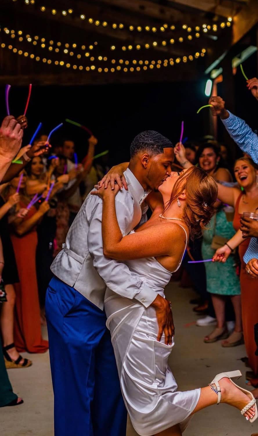 Couple dancing at Mountain Ridge Venue with guests and string lights overhead.