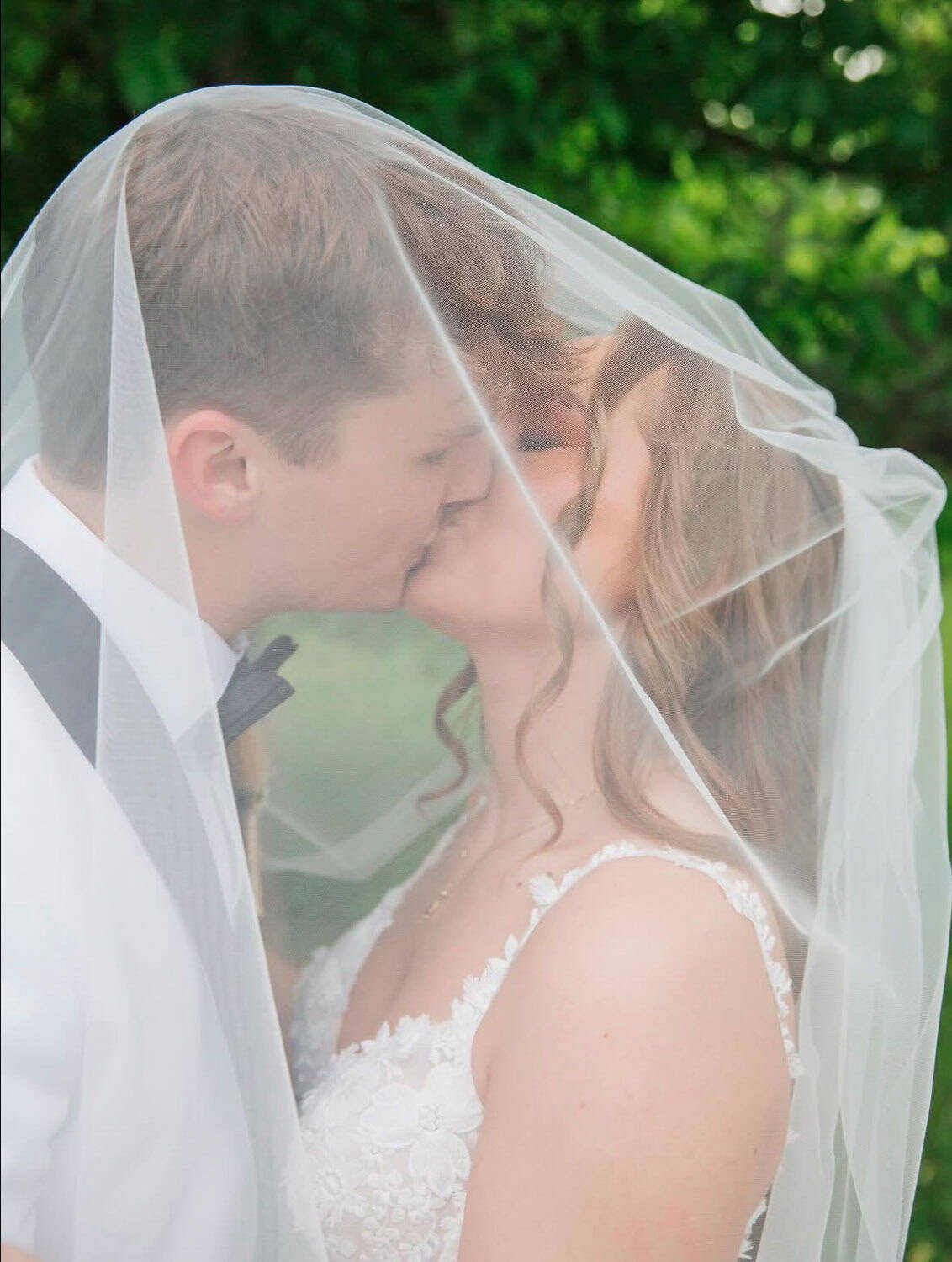 Bride and groom sharing a kiss under a veil at Mountain Ridge Venue.
