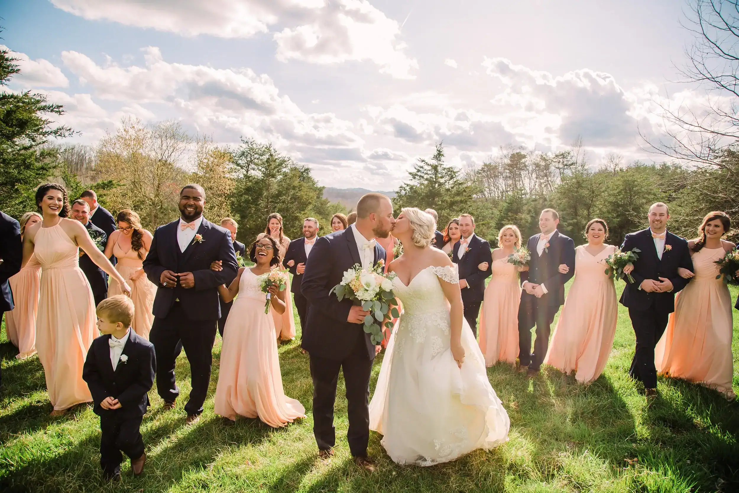 Wedding couple kissing with wedding party outdoors at Mountain Ridge.